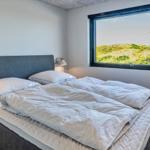 Schlafzimmer mit Doppelbett und großem Fenster zur Landschaft.