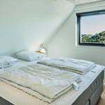 Schlafzimmer mit Doppelbett und großem Fenster mit Blick auf die Landschaft.