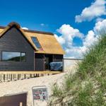 Moderne Strandhaus mit Strohdach und Holzterrasse auf Sanddüne