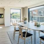 Esszimmer mit Tisch und Stühlen, große Fenster und Blick auf Außenbereich.
