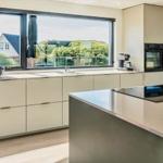 Moderne Küche mit Kücheninsel und großem Fenster zur Terrasse