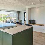 Moderne Küche mit Kücheninsel, Essbereich und Blick auf die Landschaft.