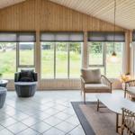 Großes Wohnzimmer mit Holzwänden und Fenstern zum Garten.