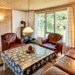 Wohnzimmer mit Holzwand, Sofa, zwei Sesseln und Kamin. Durchgang zur Schlafzimmer.