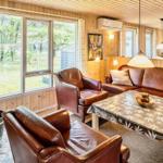 Wohnzimmer mit Holzwänden, Ledersofa, Kamin und großem Fenster.