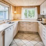 Küche mit Holzwänden, Fenstern und weißen Geräten.