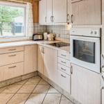 Küche mit Holzschränken, Backofen und Blick auf Außenbereich