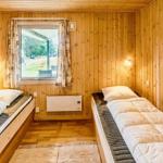 Zwei Einzelbetten in einem Holzraum mit Fenster und Heizung.