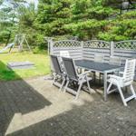 Terrasse mit Tisch und Stühlen, umgeben von einem Zaun und Grünfläche.