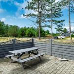 Terrasse mit Picknicktisch und Holzumrandung. Grünfläche und Bäume im Hintergrund.