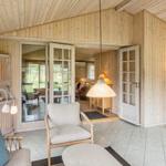 Wohnraum mit Holzwänden, Sitzmöbeln und Glas-Türen zum Garten.