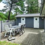 Terrasse mit Tisch und Stühlen neben einem grauen Gartenhaus.