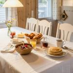 Frühstückstablett mit Pancakes, Croissants und Frühstücksgeschirr.