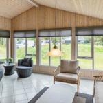 Wohnzimmer mit Holzwänden, großen Fenstern und Sitzgelegenheiten.