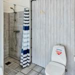 Badezimmer mit Dusche, Toilette und Whirlpool. Holzwand und Blick in die Küche.