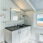 Badezimmer mit Waschbecken, Spiegel und Holzsauna