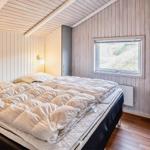 Schlafzimmer mit Bett, Nachttisch und Fenster. Holzwände und Decke.