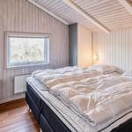 Schlafzimmer mit Bett, Fenster und Holzwandverkleidung.