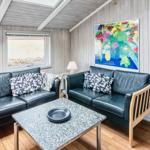 Wohnzimmer mit zwei Ledersofas, Tisch und Wandbild. Blick in Schlafzimmer mit Bett.
