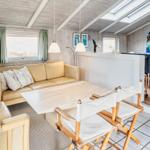 Wohnraum mit Sofa, Tisch und Stühlen. Durchgang zu Schlafzimmer mit Bett.