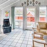 Wohnraum mit Sofa, Sessel und Kamin. Große Fenster und Tür zur Terrasse.
