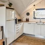 Küche mit weißem Schrank, Kühlschrank, Spüle und Fenster. Holzfußboden und Deckenbalken.