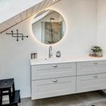 Badezimmer mit Waschbecken, Spiegel und Dusche unter Dachschräge.
