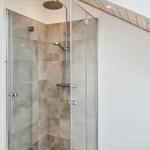 Dusche mit Glaswand, hellen Wänden und Holzdecke