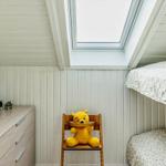 Kinderzimmer mit Doppelstockbett, Stuhl und Schrank unter Dachschräge mit Dachfenster.