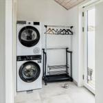 Waschmaschine und Trockner in einem Raum mit Garderobe und Tür zum Balkon.
