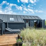 Schwarzes Haus mit Terrasse und Liegen im Gras