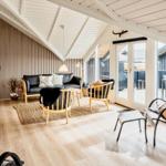 Wohnraum mit Sofa, Sitzgelegenheiten und großem Fensterbereich.