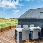 Terrasse mit Tisch und Stühlen neben einem Haus mit grauem Dach.