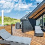 Terrasse mit Liegen, Tisch und Stühlen. Blick auf grüne Hügel. Modernes Haus mit Glasfront.