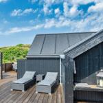Terrasse mit Liegen und Sitzbank neben einem dunklen Holzhaus.