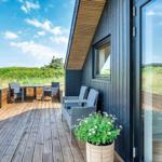Terrasse mit Sitzgruppe und Tisch. Hintergrund: Grünflächen und blauer Himmel.