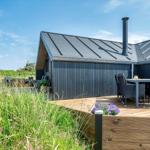 Moderne Hütte mit Holzterrasse, Gartenmöbeln und Grillmöglichkeit im Freien.