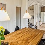 Essbereich mit Holztisch und schwarzen Stühlen. Im Hintergrund Wohnzimmer und Küche.
