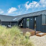 Moderne Strandhütte mit Terrasse und Sitzgelegenheiten.