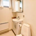 Badezimmer mit Waschbecken, Spiegelschrank und Toilette. Fenster mit Vorhängen und Heizkörper.