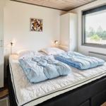 Schlafzimmer mit Doppelbett, Fenster und Kleiderhaken an der Wand.