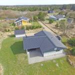Haus mit dunklem Dach und Terrasse auf grünem Grundstück