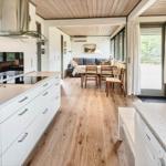 Moderne Küche mit Essbereich und Wohnzimmer. Holzboden und große Fenster.