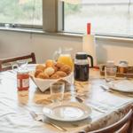 Gedeckter Esstisch mit Frühstück, Holzstühle, Fensterblick