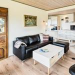 Wohnzimmer mit Sofa, Sessel und Küchenbereich im Hintergrund.