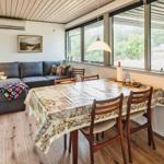 Wohn- und Essbereich mit Sofa, Tisch und Stühlen. Große Fenster mit Blick auf die Landschaft.
