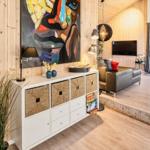 Wohnzimmer mit Holzwand, Sofa, Fernseher und großem Fenster zur Terrasse.