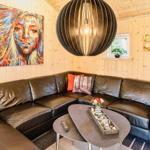 Schwarzes Ledersofa mit Kissen, runder Tisch und Wandbild in Holzwandung.