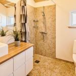 Badezimmer mit Dusche, Toilette und Waschtisch mit Holzplatte.