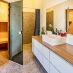 Badezimmer mit Dusche, Waschtisch und Holzsauna